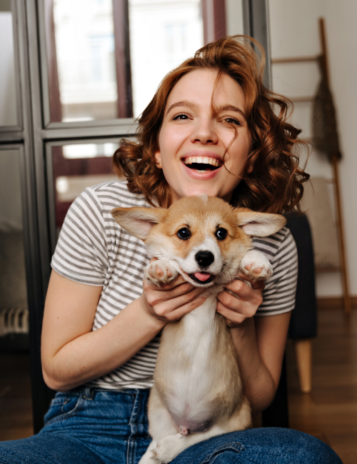 positive-woman-sits-floor-living-room-with-smile-plays-with-her-beloved-dog